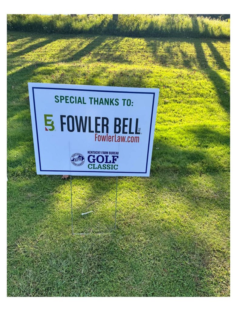 A Fowler Bell lawn sign standing in grass.