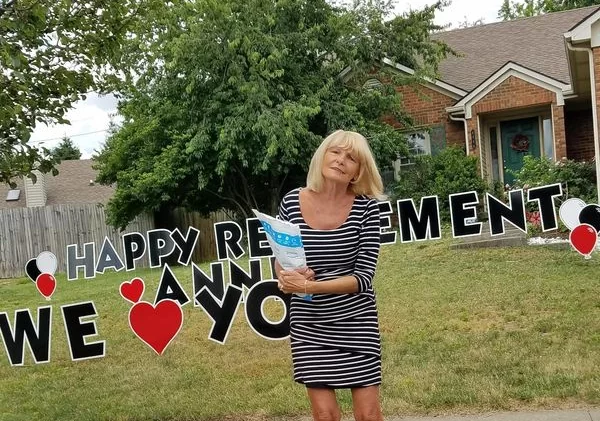 Anne Jasser smiling in front of retirement decorations
